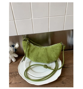 Détail du sac croissant en daim vert avec coutures verticales et bandoulière nouée