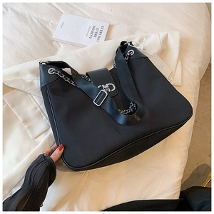 Close-up of black nylon tote bag featuring silver chain links and metal buckle accents