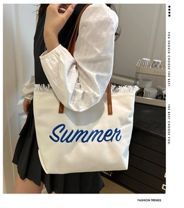 Détail du sac cabas en toile blanche avec broderie Summer bleue et bords frangés