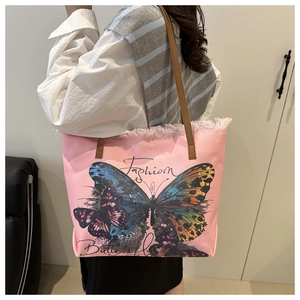 Detail view of pink canvas tote bag with butterfly prints and fringe trim edge