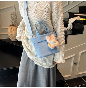 Détail d'un sac cabas bleu clair en tissu Oxford avec un joli pendentif ours