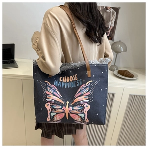 Detail of canvas tote bag with butterfly print, fringe edges, and leather handles
