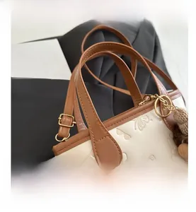 Detail of embossed patterns and brown leather strap on cream-colored bucket bag
