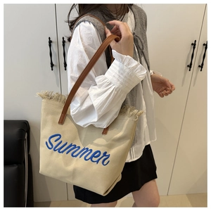 Dettaglio della borsa in tela beige con ricamo Summer blu, frange e tracolla in pelle marrone