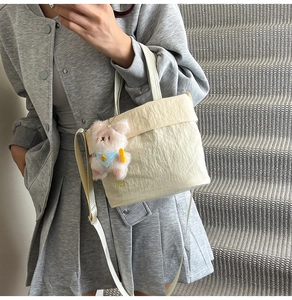Sac seau plissé beige en tissu Oxford avec charm lapin porté par un mannequin