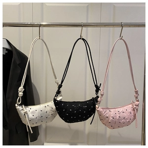 Close-up of three quilted half-moon shoulder bags with small black bow patterns