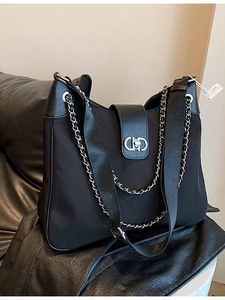 Black soft leather tote with silver chain accent and metallic clasp on a dark surface