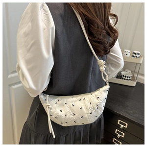 Back view of a white crescent shoulder bag with black bow embroidery and knotted rope strap