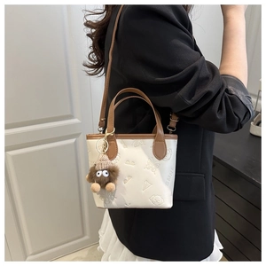 Detail of crossbody bucket bag with fun embossing and a cute plush doll charm