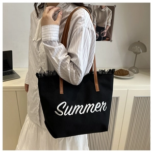 Détail du sac fourre-tout en toile noire avec lettrage summer et anses en cuir brun