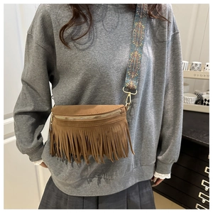 Brown suede half-moon bag featuring dense fringe detail and wide bohemian print strap