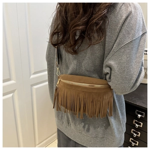 Close-up of brown suede saddle bag with decorative tassels and patterned strap