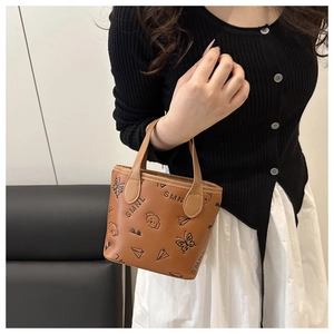 Detailed view of brown bucket bag featuring embossed butterfly and bear patterns