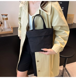 Détail du sac seau en nylon noir avec poignées supérieures et logo gaufré élégant