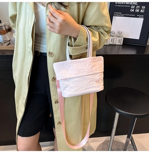 Détail d'un sac seau plissé rose clair en tissu Oxford avec bandoulière en nylon