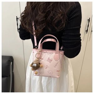 Detail of pink bucket bag with puppy prints and a brown plush monster charm on a model