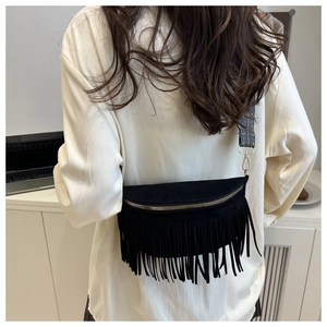 Detail of black suede fringe crossbody bag with bohemian style long tassels and woven strap