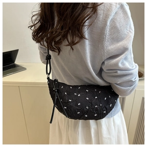Detailed back view of a black quilted crescent bag with white bow embroidery on shoulder