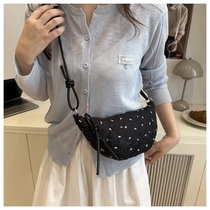 Detail of black crescent bag with white bow embroidery and knotted strap design