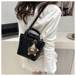 Mini black embossed tote bag with a cute plush monster pendant and slim shoulder strap