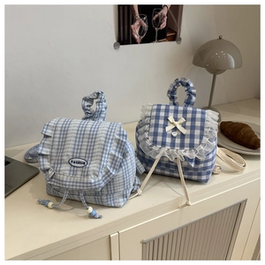 Close-up of blue plaid mini backpacks with delicate lace ruffles and bow details