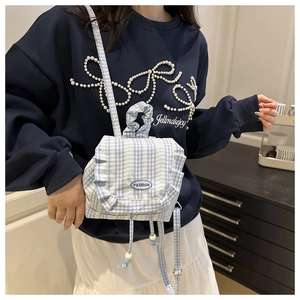 Detail of light blue plaid backpack with ruffle edges and drawstring fashion handle