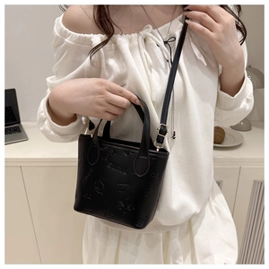 Detail of black embossed bucket bag featuring SMNL patterns and gold-toned metal hardware