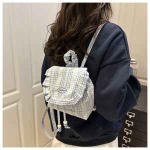 Detail of blue plaid backpack with frill trim and beaded drawstring in a lifestyle setting