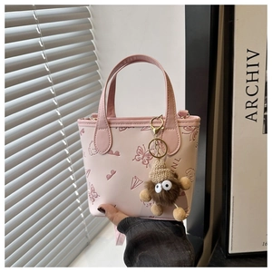 Detail of pink faux leather bucket bag with butterfly embossing and plush doll charm