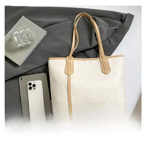 Detail of white embossed tote bag showing spacious interior with tablet and accessories