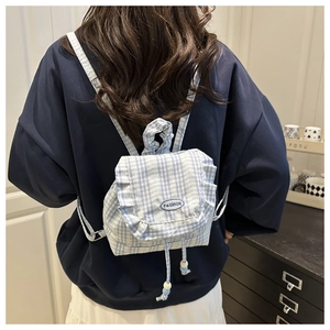 Macro detail of blue gingham mini backpack with lace trim and fashion embroidery