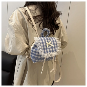 Detail of blue plaid mini backpack with white lace ruffles and a small bow decoration