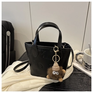 Detail of embossed butterfly and bear pattern on a black leather crossbody bag
