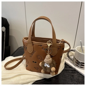 Close-up of brown leather tote with butterfly print and cute plush charm detail