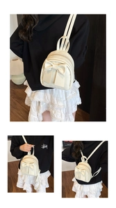 Detail shot of a cream PU leather mini backpack featuring a large decorative bow