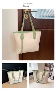 Detail of light green handles and embossed pattern on the large cream tote bag