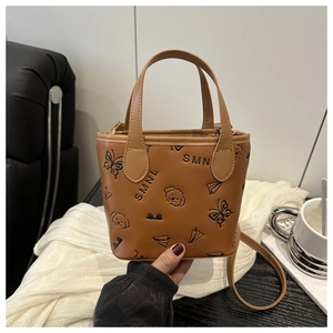 Detail showing embossed butterfly and puppy patterns on brown PU leather bucket bag