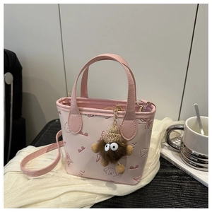 Detail of pink embossed mini tote with puppy patterns and a cute brown plush monster charm