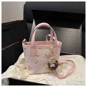 Pink embossed bucket bag with butterfly patterns and a cute plush monster charm