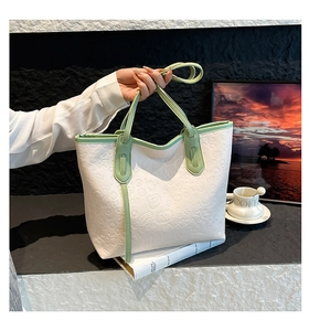 Détail du sac cabas blanc avec anses vertes et motifs embossés de cœurs et d'étoiles