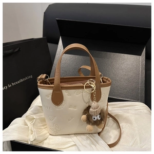 Detail of mini bucket bag with embossed patterns and cute plush monster charm accessory