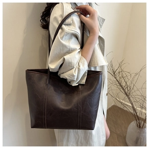 Dettaglio della grande borsa tote marrone scuro con texture stropicciata retrò sulla spalla