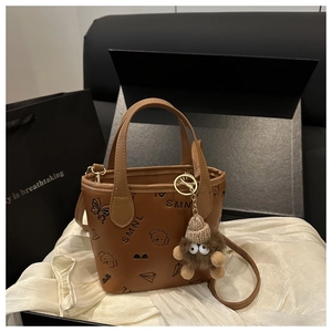 Close-up of brown PU leather bucket bag featuring whimsical black embossed sketches