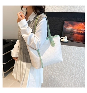 Detail of white tote bag with green handles and embossed cartoon pattern texture