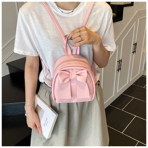 Detailed view of pink mini backpack featuring a large bow and premium glossy finish