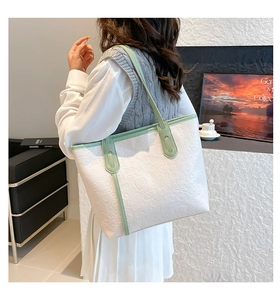 Detail of white tote bag with green trim and all-over embossed cartoon graffiti pattern