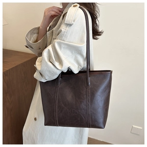 Dettaglio della trama e del logo impresso della borsa tote vintage in pelle marrone