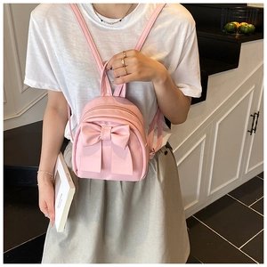 Detail of pink mini backpack featuring a large decorative bow and nylon texture