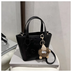 Detail of black embossed leather bucket bag with butterfly motif and cute monster charm