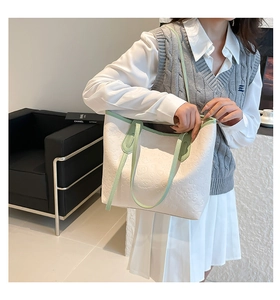 Close-up of a white tote bag with green trim and embossed cartoon pattern for women